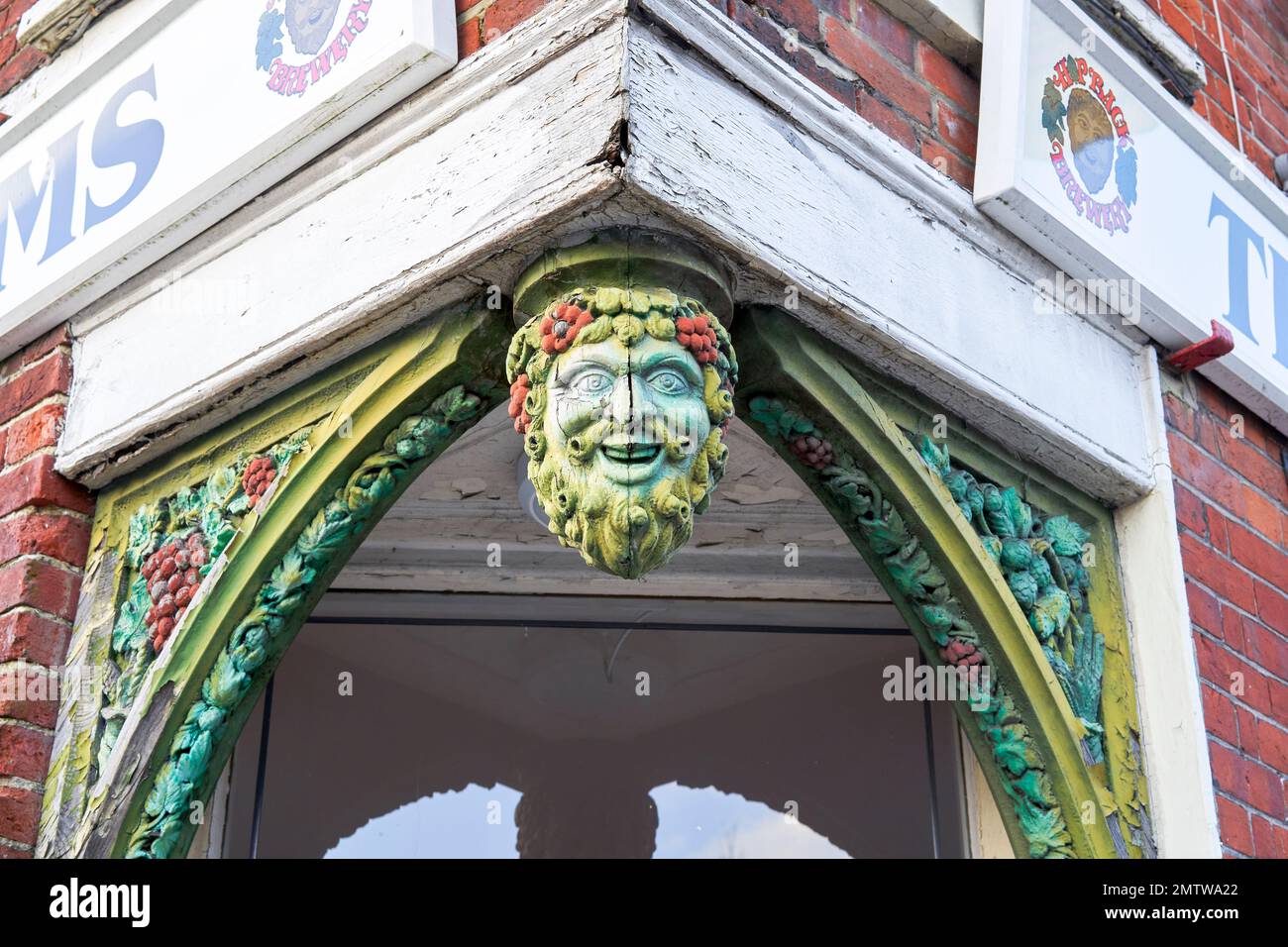 Tête en bois sculpté et face de l'homme vert suspendu au-dessus de l'entrée d'une maison publique Banque D'Images