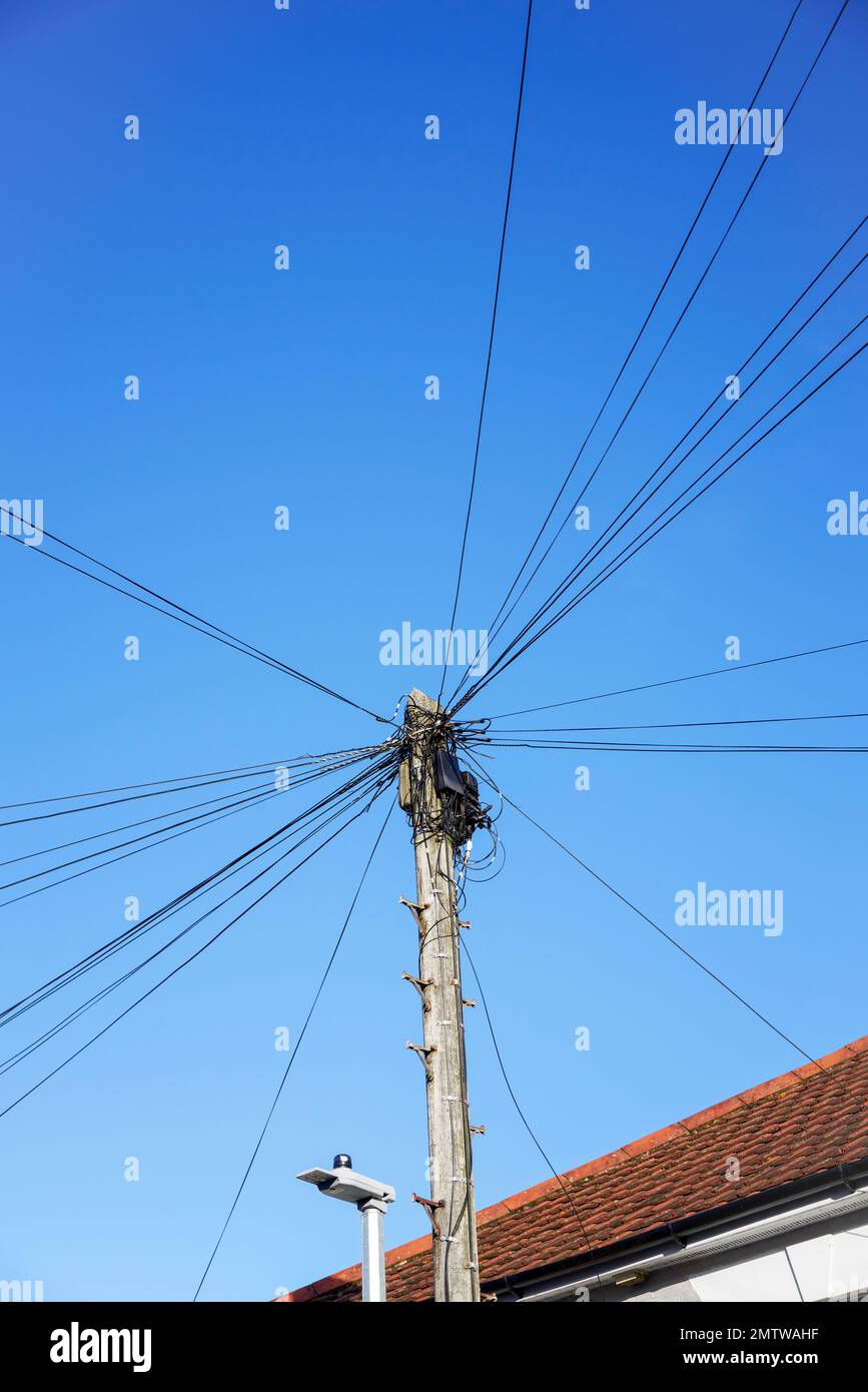 Câbles téléphoniques et boîtier de raccordement au sommet d'un poteau en bois contre le ciel bleu Banque D'Images