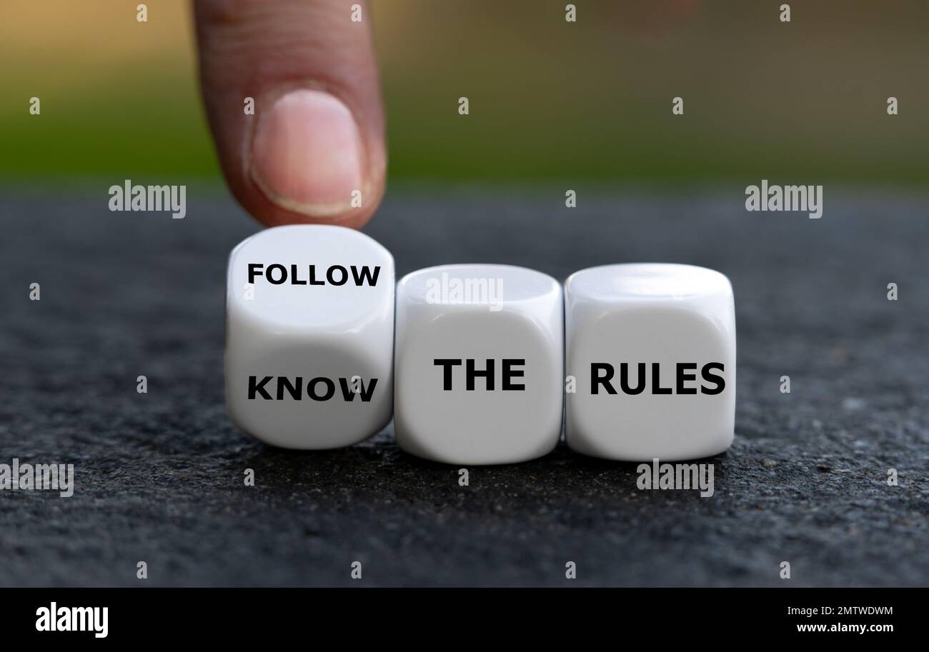 La main tourne les dés et change l'expression « connaître les règles ». pour « suivre les règles ». Banque D'Images
