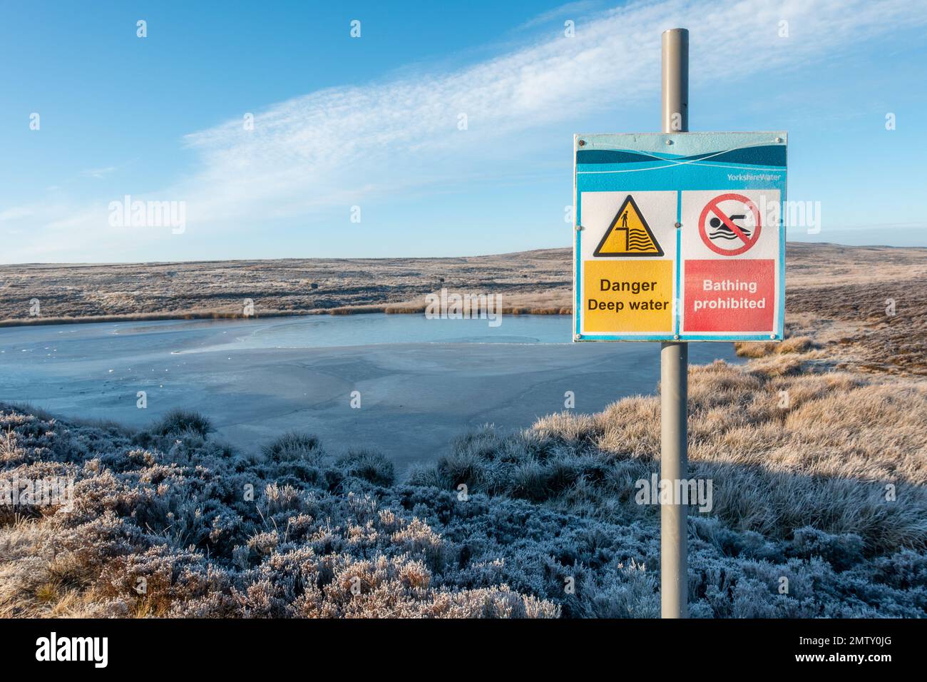 Signe de danger à côté d'un réservoir surgelé disant danger eau profonde et baignade interdite sur Burley Moor à côté de Ilkley Moor par un froid hiver, Banque D'Images