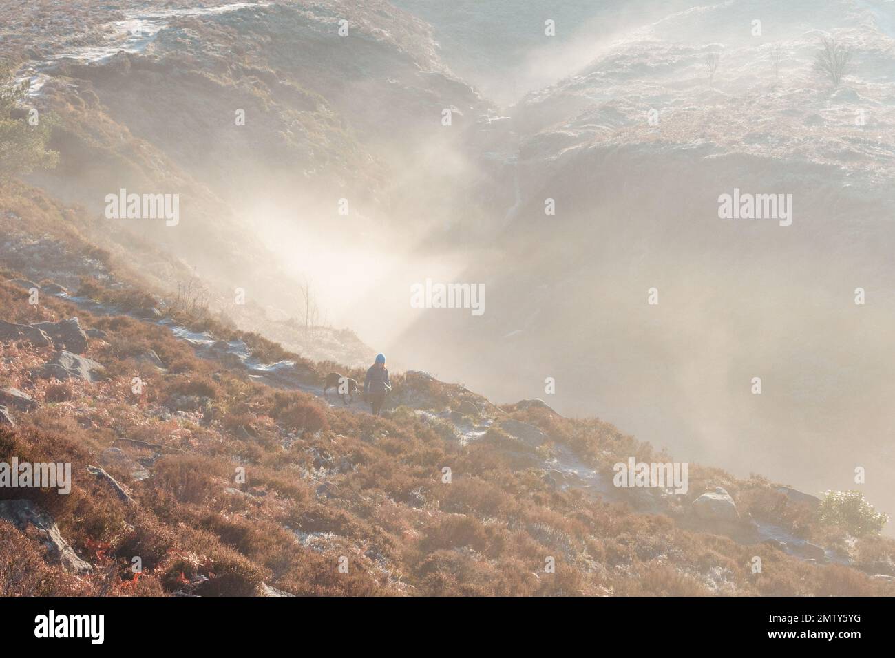Une femme marchant sur un chemin le long d'un froid hiver sur Ilkley Moor avec un peu de brume de moody tourbillonnant créant l'atmosphère dans le fond et un lourd Banque D'Images