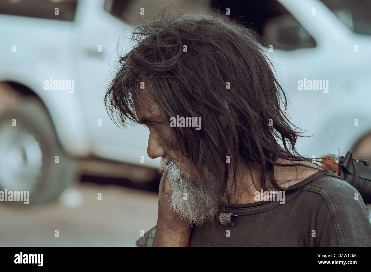 Un petit foyer d'un mendiant mâle avec de longs cheveux peu accrochés et une barbe dans une rue à Batangas, Philippines Banque D'Images