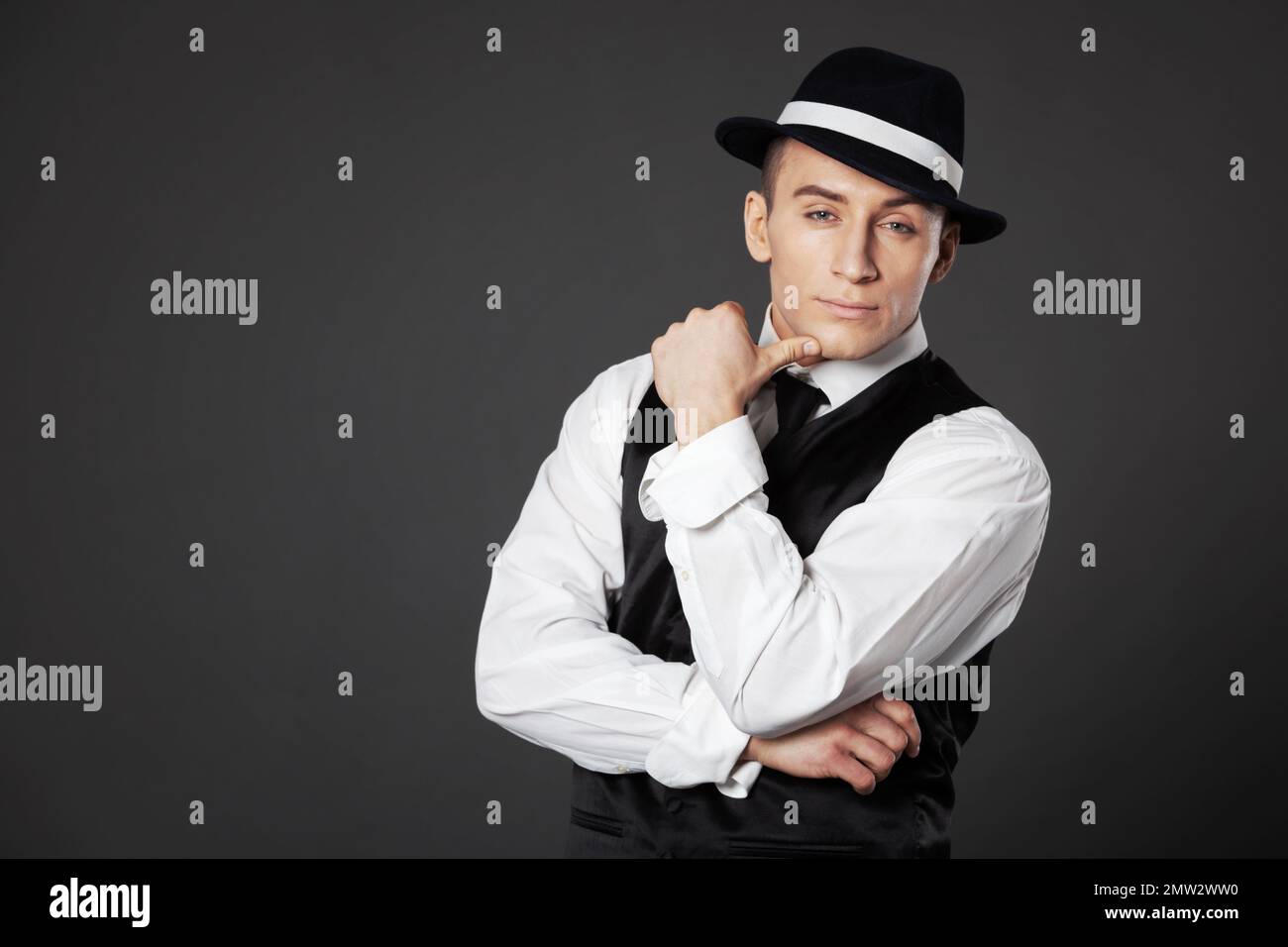 Jeune homme confiant posant dans une suite de style gangster. Studio isolé sur fond gris. Banque D'Images