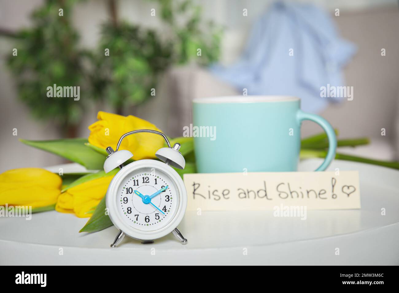 Réveil, café du matin aromatique, belles fleurs et carte avec LEVER ET BRILLER sur table blanche à l'intérieur Banque D'Images