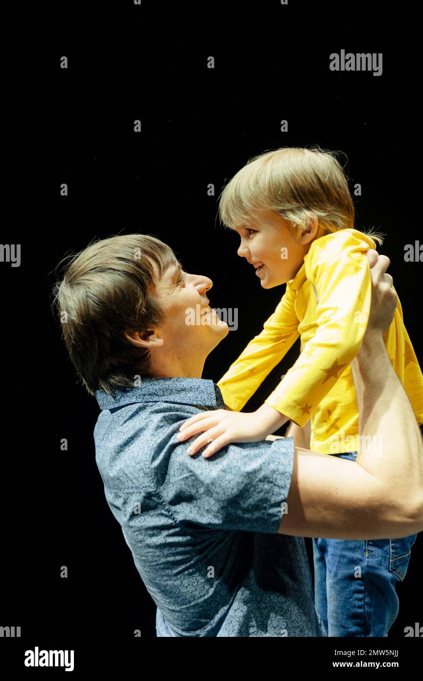 homme père papa tient petit garçon garçon fils de six ans dans ses bras et ses hugs. famille heureuse, parentalité, paternité et enfance en studio éclairé b Banque D'Images