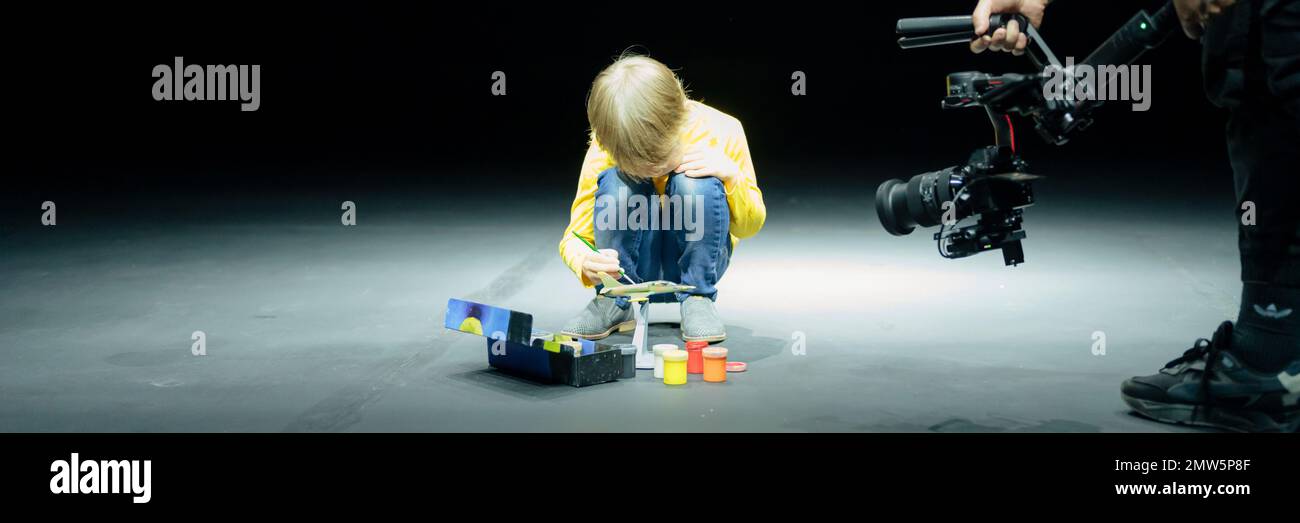 Russie, Moscou 06.15.2022. le vidéaste tourne sur caméra vidéo, comme petit garçon de six ans peinture ou coloriser ou modèle couleur d'avion avec goua Banque D'Images
