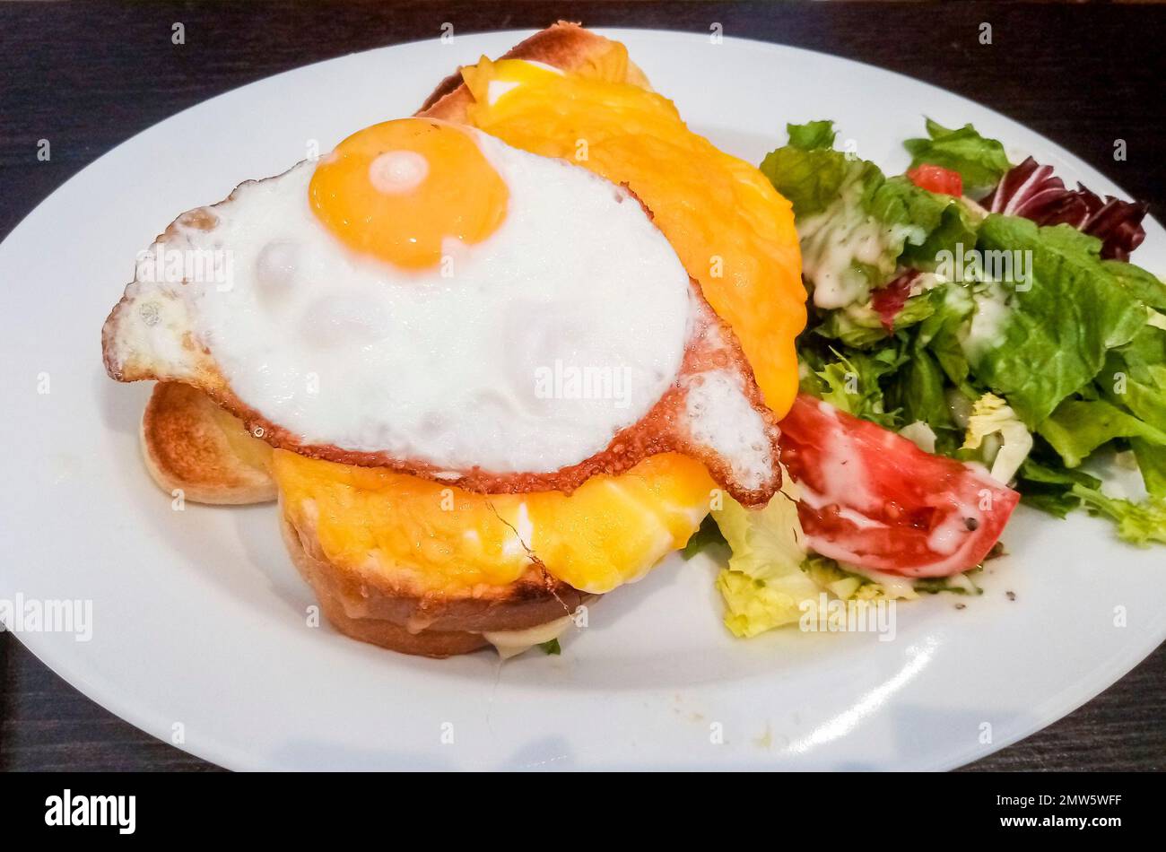 Croque Madame, plat de jambon et de fromage français sur du pain beurré avec œuf sur le dessus. Banque D'Images