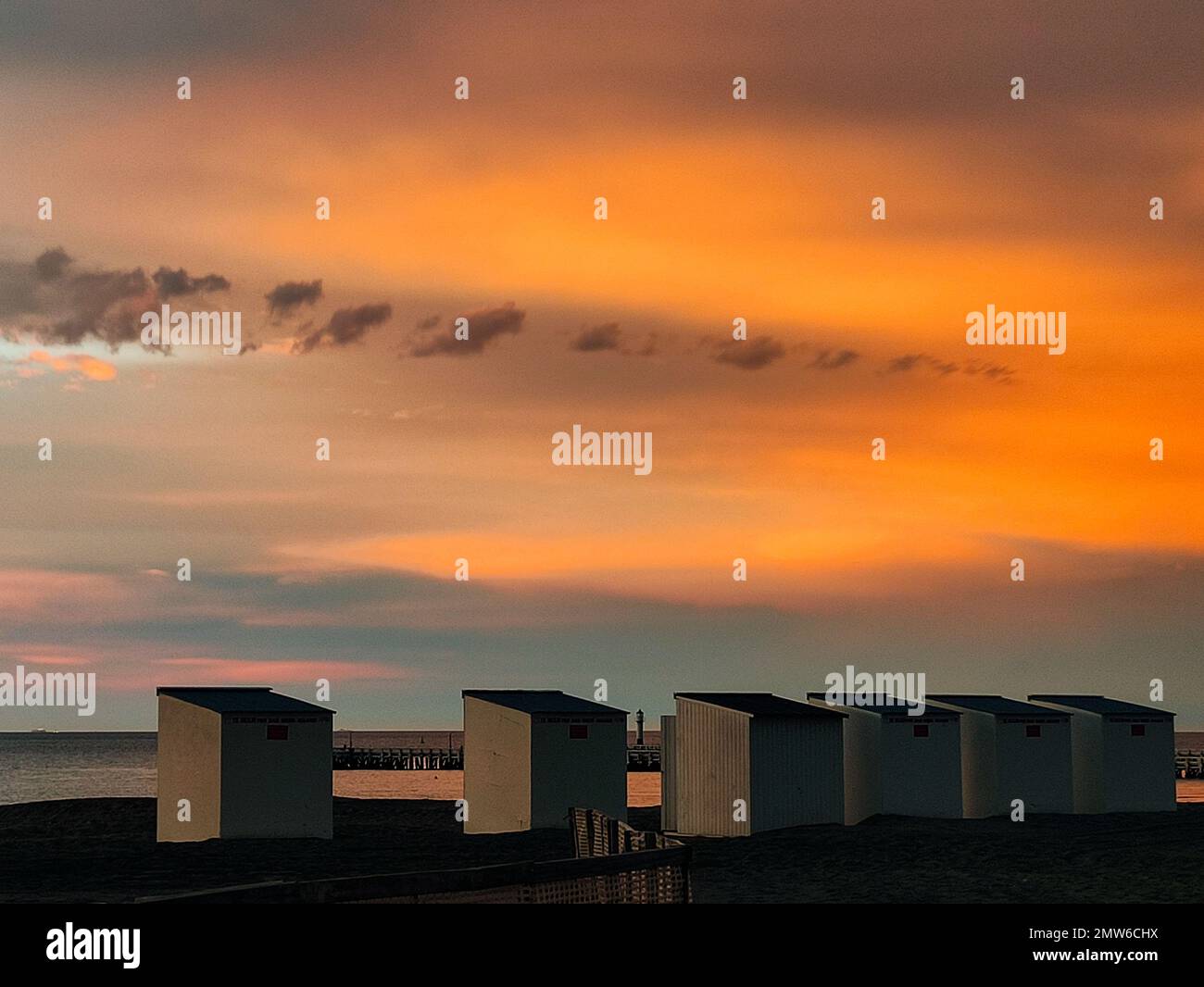 Coucher de soleil spectaculaire sur la plage de la côte océanique de la mer de Nieuwpoort avec silhouette de petites cabanes en rangée Banque D'Images