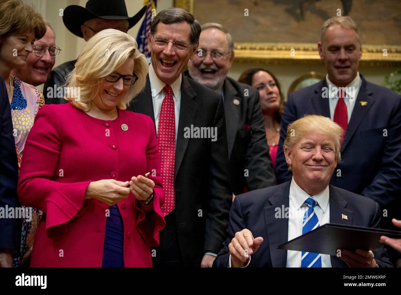 President Donald Trump gives his pen to Rep. Liz Cheney, R-Wyo., third from left, after signing one of various bills in the Roosevelt Room of the White House in Washington, Monday, March 27, 2017. From left are, Sen. Lisa Murkowski, R-Alaska, Sen. Lamar Alexander, R-Tenn., Sen. John Barrasso, R-Wyo., Rep. Don Young, R-Alaska and Interior Secretary Ryan Zinke, right, and his wife Lolita, second from right. (AP Photo/Andrew Harnik) Banque D'Images