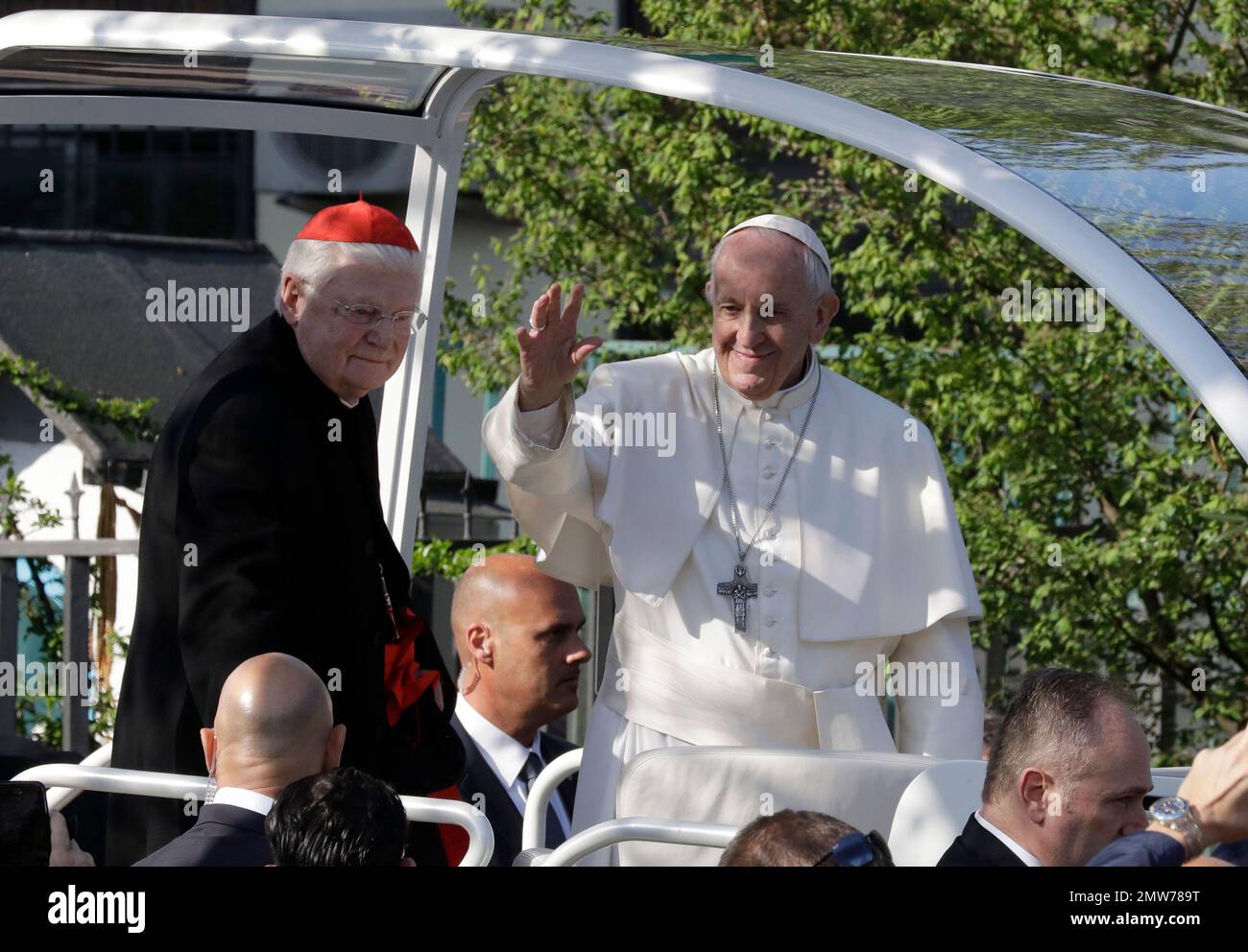 Pope Francis, flanked by Cardinal Angelo Scola, left, waves as he arrives  at Milan's Forlanini neighborhood known as Case Bianche (white houses), as  part of his one-day pastoral visit to Monza and