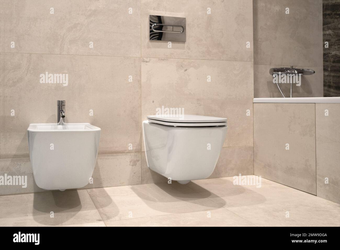 bidet et toilettes muraux blancs, carrelage en céramique grise dans la salle de bains. Espace de vie minimaliste en gros plan Banque D'Images