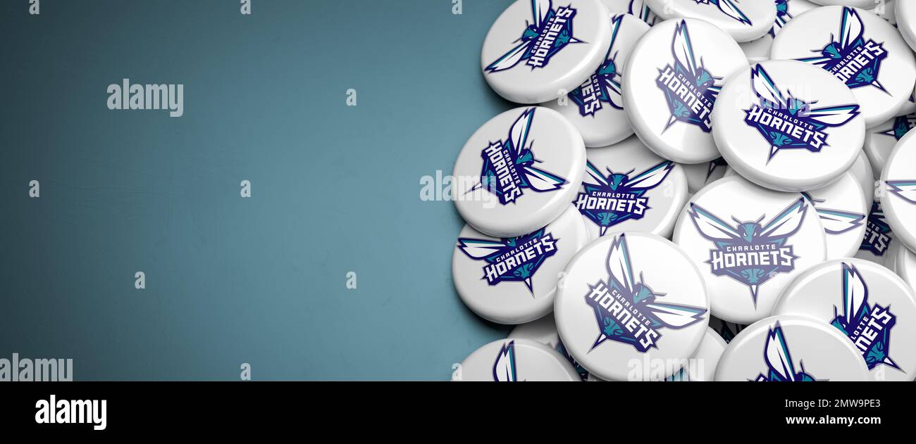 Logos de l'équipe américaine de basket-ball de la NBA Charlotte Hornets sur un tas sur une table. Banque D'Images