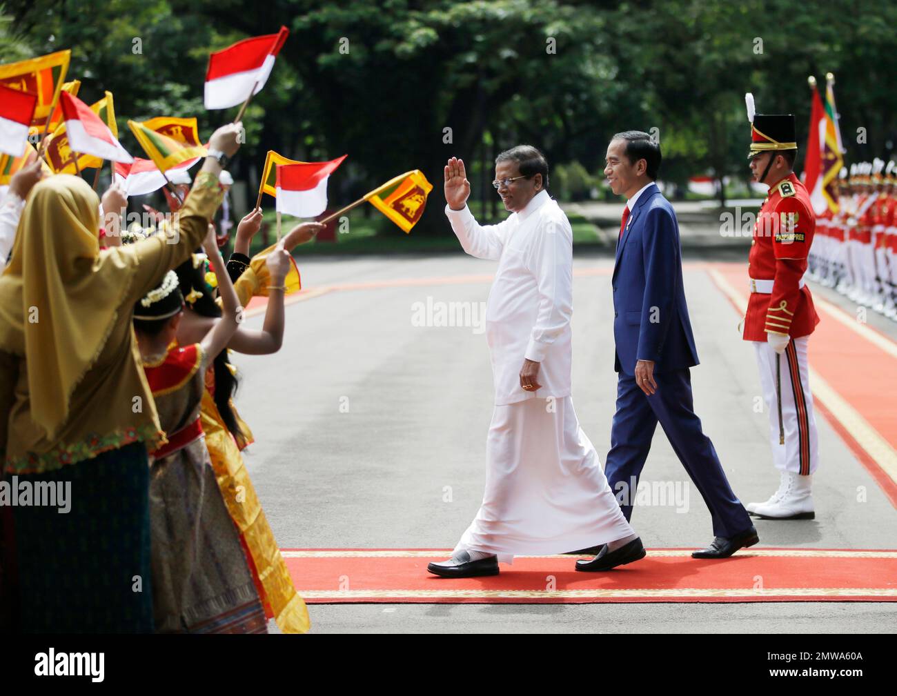 Sri Lankan President Maithripala Sirisena,center left, walks with his Indonesian counterpart Joko Widodo, center right, as school children in traditional dress wave the national flags of the two countries during a welcome ceremony at Merdeka Palace in Jakarta, Indonesia, Wednesday, March 8, 2017. (AP Photo/Achmad Ibrahim) Banque D'Images