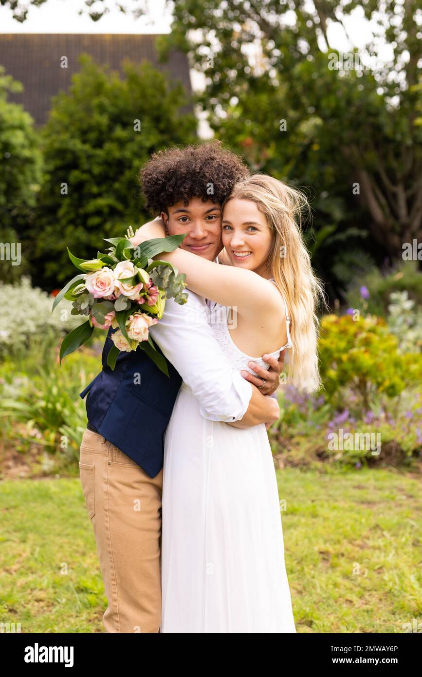Portrait vertical de la mariée et du marié heureux et variés embrassant au mariage dans le jardin Banque D'Images