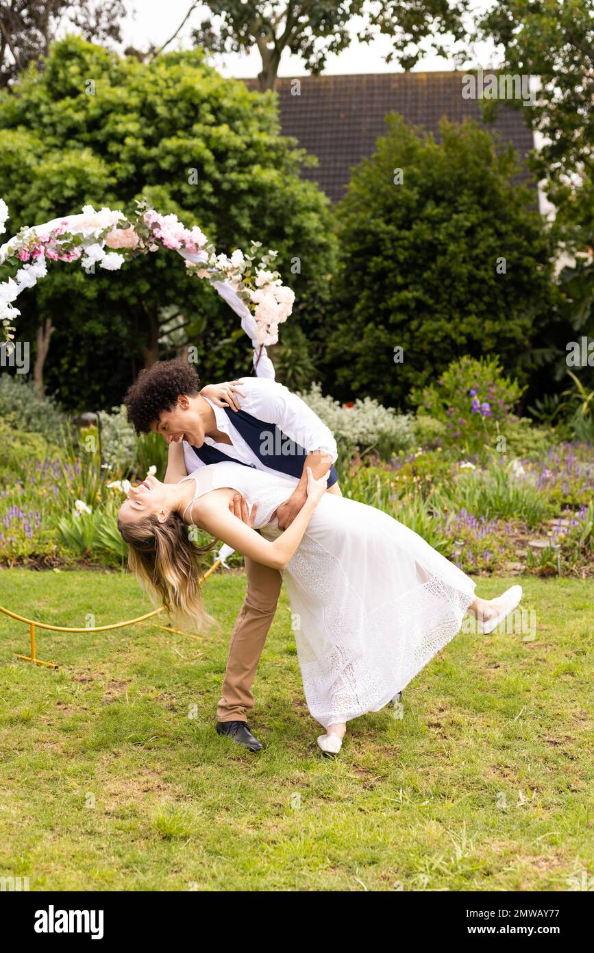 Vertical de heureux divers mariés embrassant, dansant au mariage dans le jardin, espace de copie Banque D'Images