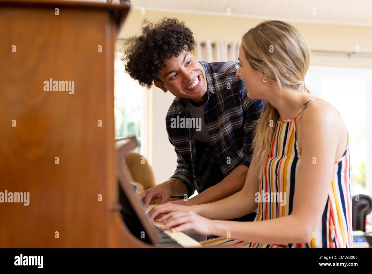 Joyeux couple divers ayant plaisir à jouer du piano ensemble à la maison, l'espace de copie Banque D'Images