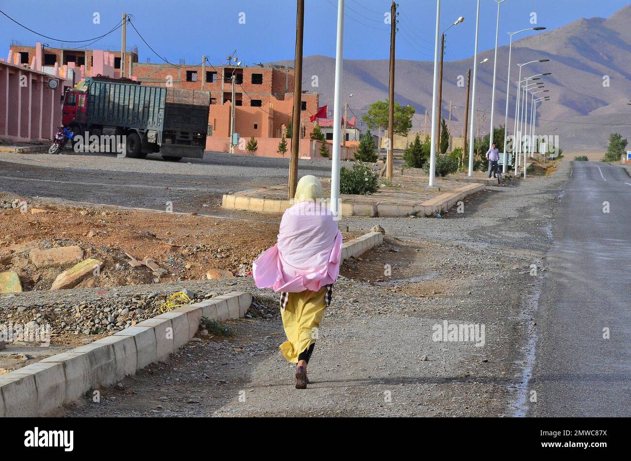 Femme marchant sur la chaussée devant le nouveau domaine de logement en construction, Maroc Banque D'Images