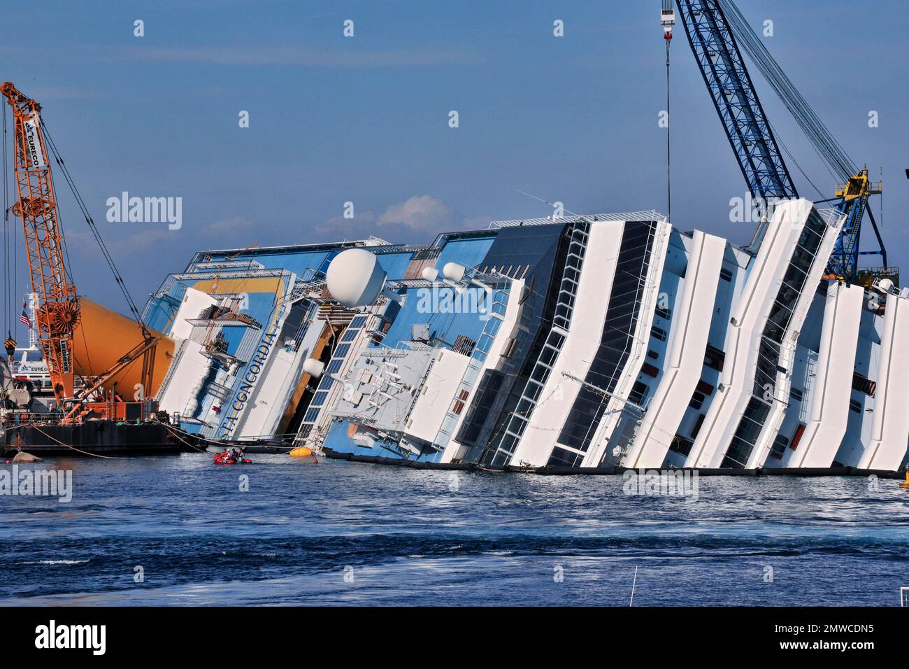 Vue sur le pont supérieur du bateau de croisière chaviré avec le nom de Costa Concordia visible, derrière elle une grue de sauvetage, Giglio Porto, Giglio Island Banque D'Images