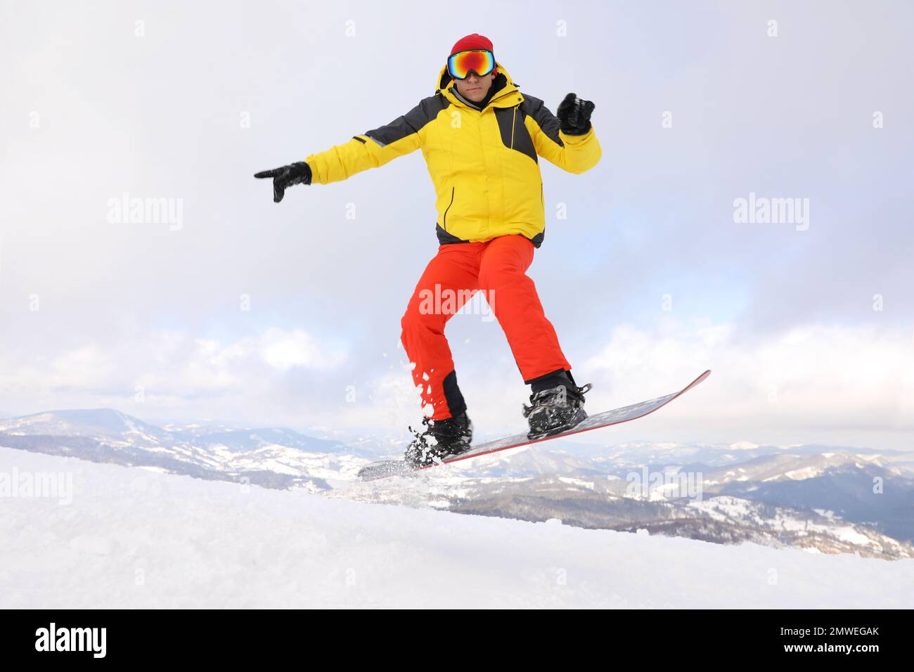 Snowboardeur mâle sur une colline enneigée. Vacances d'hiver Banque D'Images