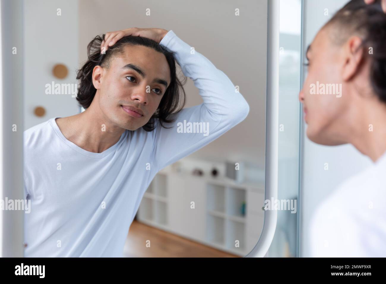 Joyeux biracial homme regardant dans le miroir dans la salle de bains Banque D'Images