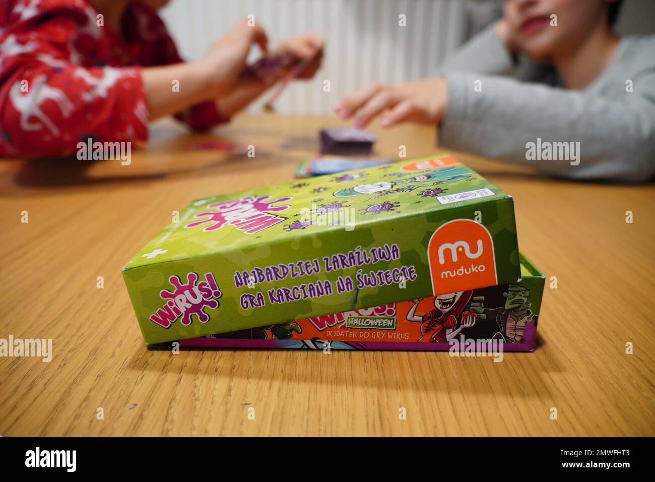 Les enfants assis à côté de la table et jouant au jeu de cartes Muduko Polish Wirus Banque D'Images