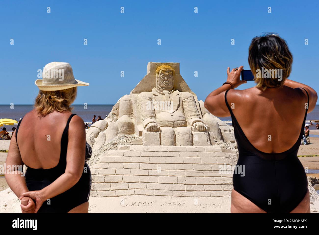 Women look at a sand sculpture in the likeness of President Donald Trump sitting behind a wall, during the Fourth Latin American Sand Sculpture Gathering in the beach town of Marindia, Uruguay, Sunday, Jan. 29, 2017. Artists from Argentina, Brazil, Colombia, El Salvador, Mexico, Paraguay, Peru and Uruguay participated in the four day event, exhibiting their talents along the coastline. (AP Photo/Matilde Campodonico) Banque D'Images