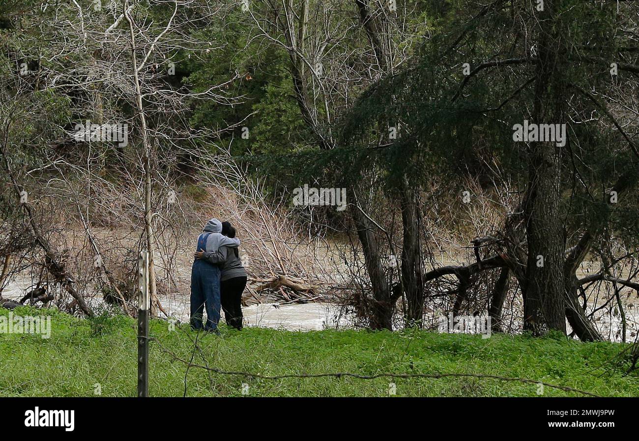 The mother of a missing 18-year-old woman, right, is embraced at what they believe is the location where her daughter's car lies submerged in Alameda Creek on Monday, Jan. 23, 2017 on Niles Canyon Road near Fremont, Calif. The unidentified woman's car plunged into rushing waters after colliding with another vehicle on Saturday, Jan. 21, 2017, and she is suspected as being in the submerged vehicle. (AP Photo/Ben Margot) Banque D'Images