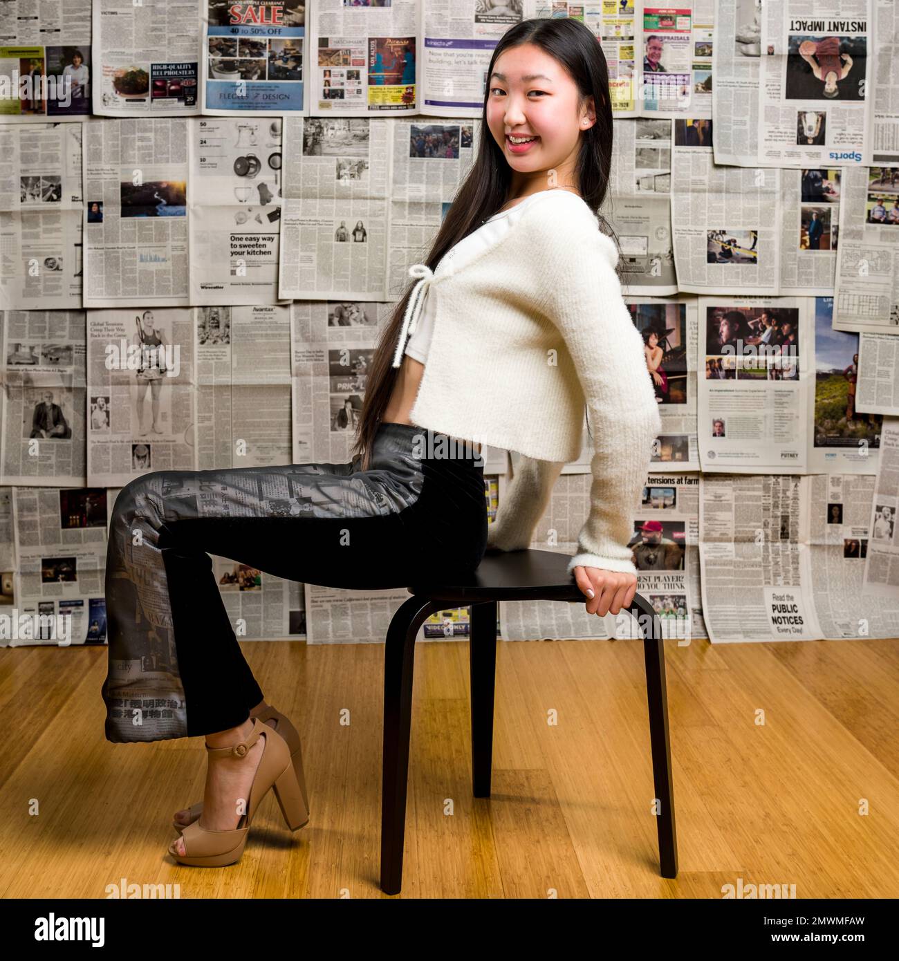 Grand corps Teenage Asian Girl assis devant la toile de fond des journaux Banque D'Images