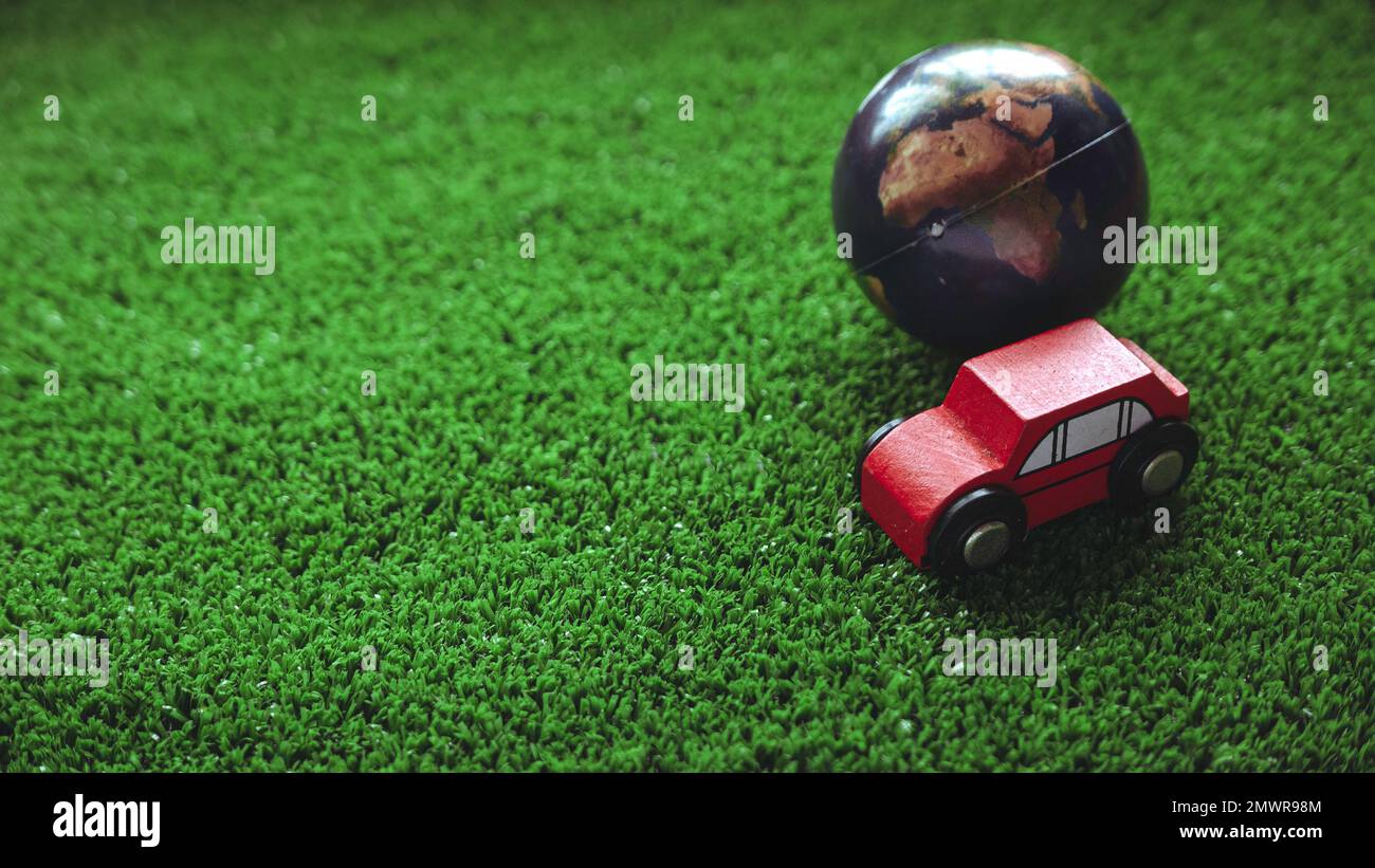 Une voiture de jouets et un globe sur un gazon vert. Concept de véhicule écologique. Banque D'Images