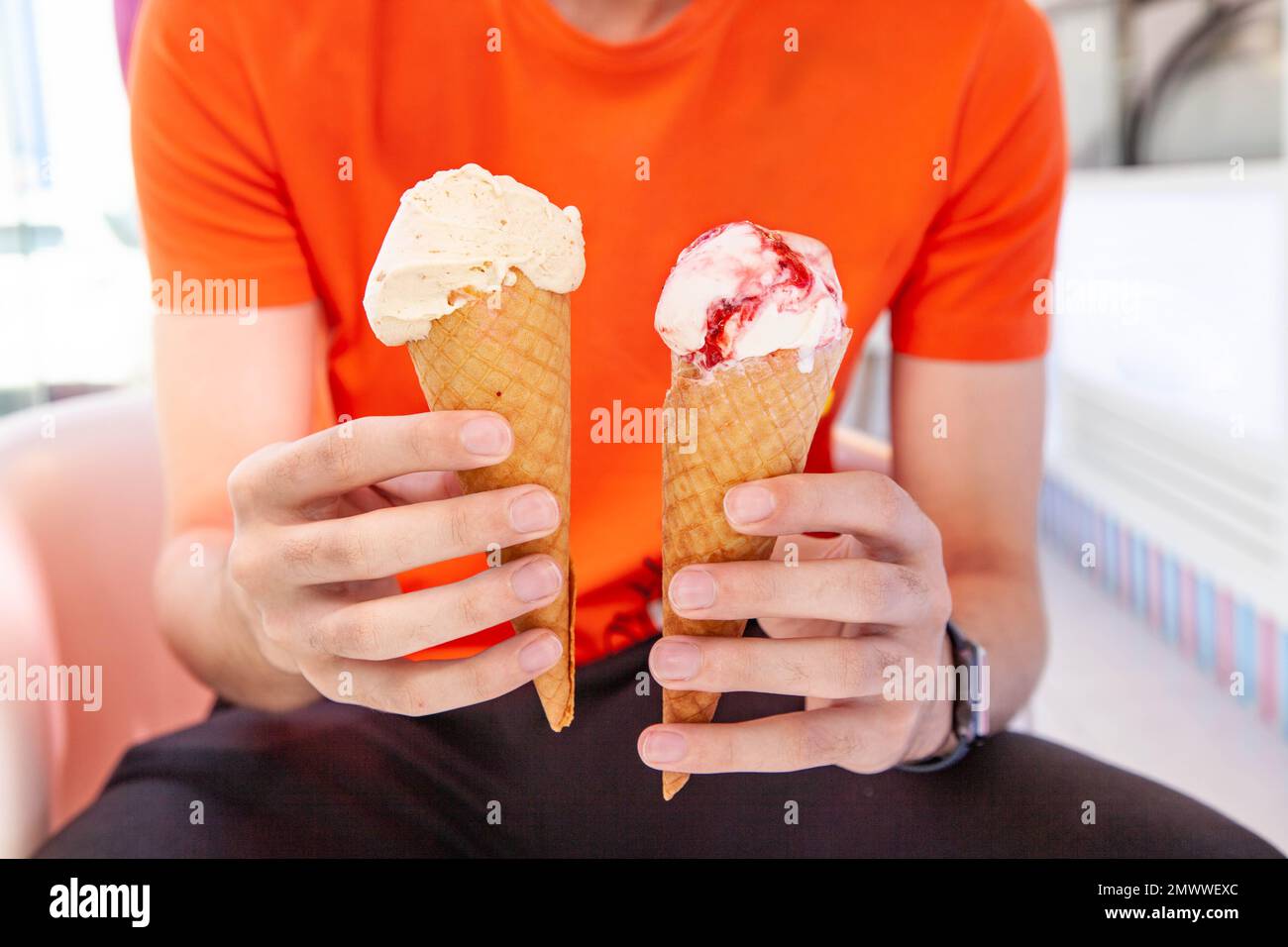 Main tenant la glace à glace à cône en deux mains Banque D'Images