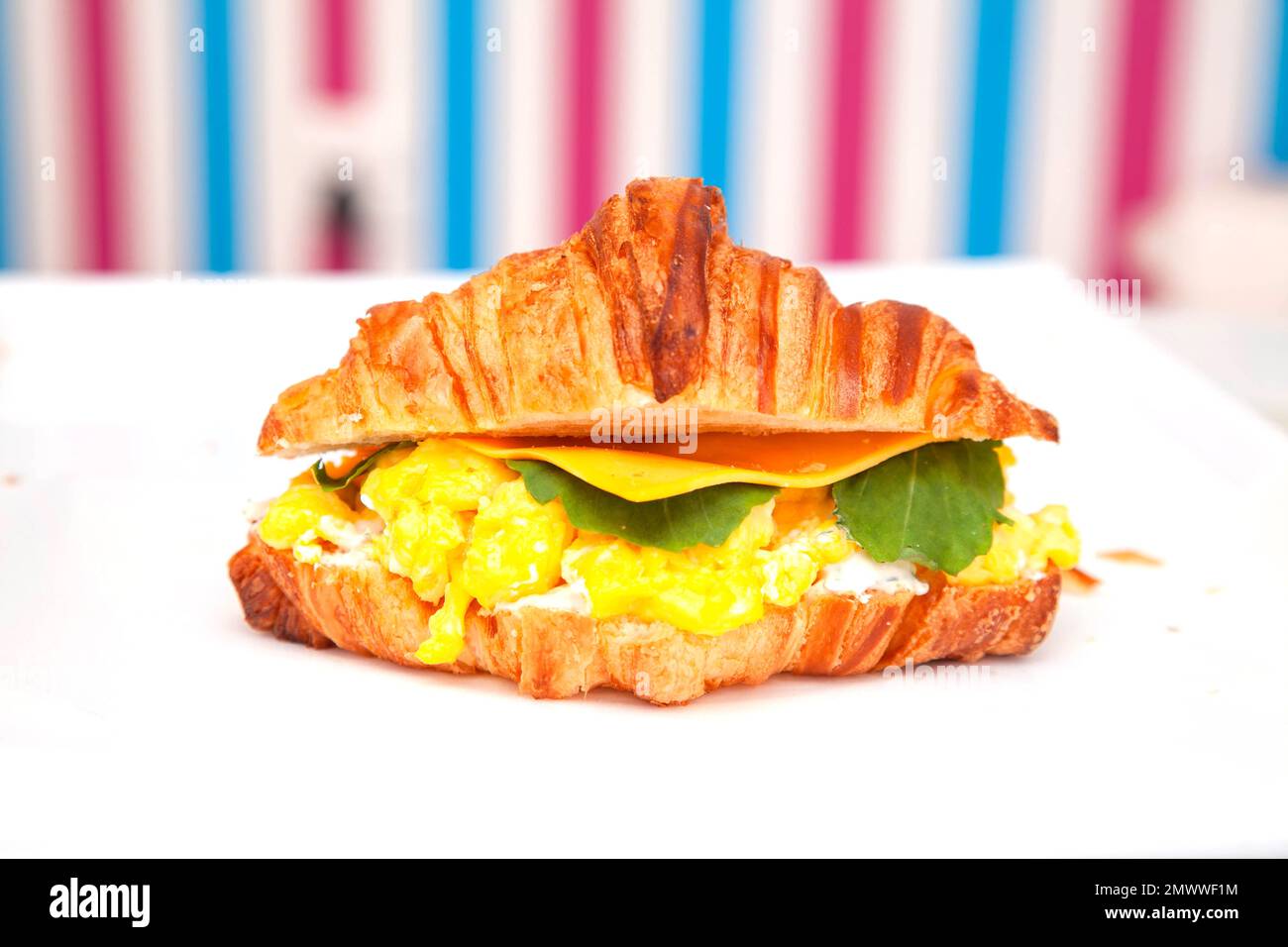 Petitdéjeuner sandwich brioché croissant avec fromage aux œufs brouillés et feuille de roquette