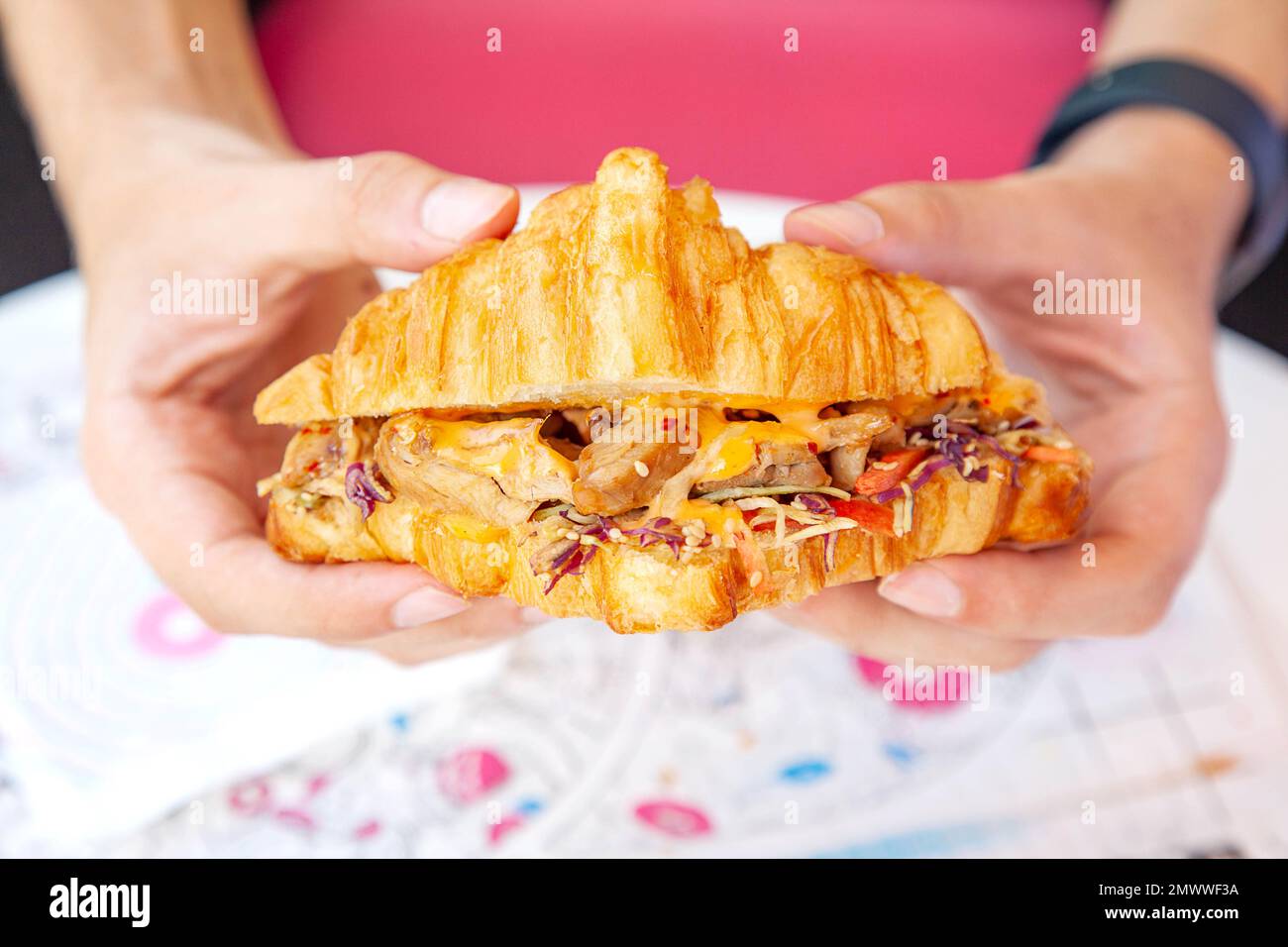 Brioche croissant poulet grillé sandwich à la main dans la photographie de la nourriture de style de vie. Banque D'Images