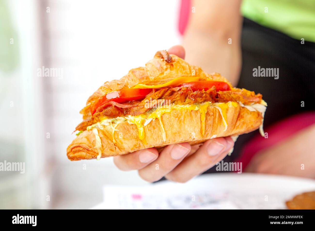 Brioche croissant poulet grillé sandwich à la main dans la photographie de la nourriture de style de vie. Banque D'Images
