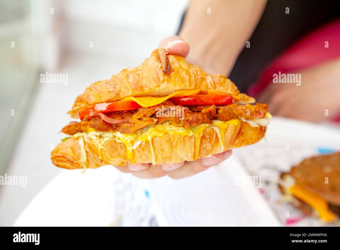 Brioche croissant poulet grillé sandwich à la main dans la photographie de la nourriture de style de vie. Banque D'Images