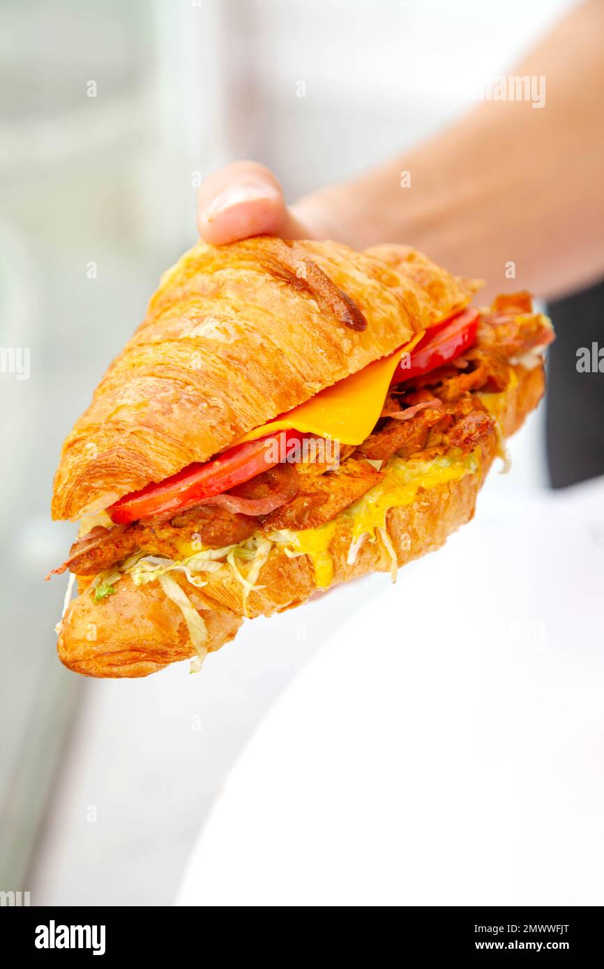 Brioche croissant poulet grillé sandwich à la main dans la photographie de la nourriture de style de vie. Banque D'Images