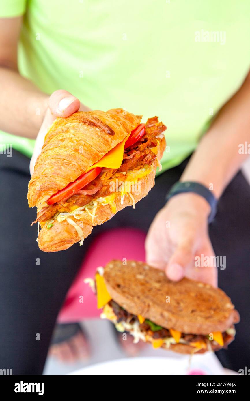 Brioche croissant poulet grillé sandwich dans deux mains style de vie photographie alimentaire. Banque D'Images