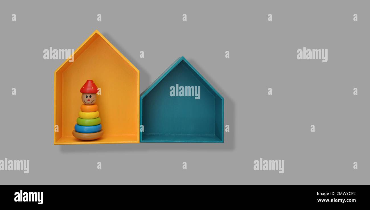 Étagères élégantes en forme de maison avec jouets sur un mur gris. Décoration intérieure pour les chambres de bébé et de tout-petit, espace de photocopie Banque D'Images