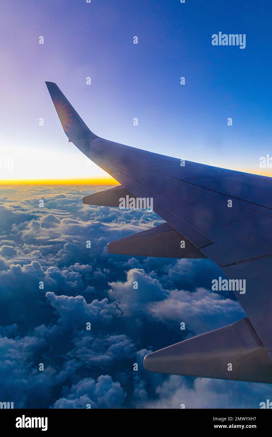 Vue depuis la fenêtre passager d'un Boeing 737 survolant des nuages au coucher du soleil. Banque D'Images