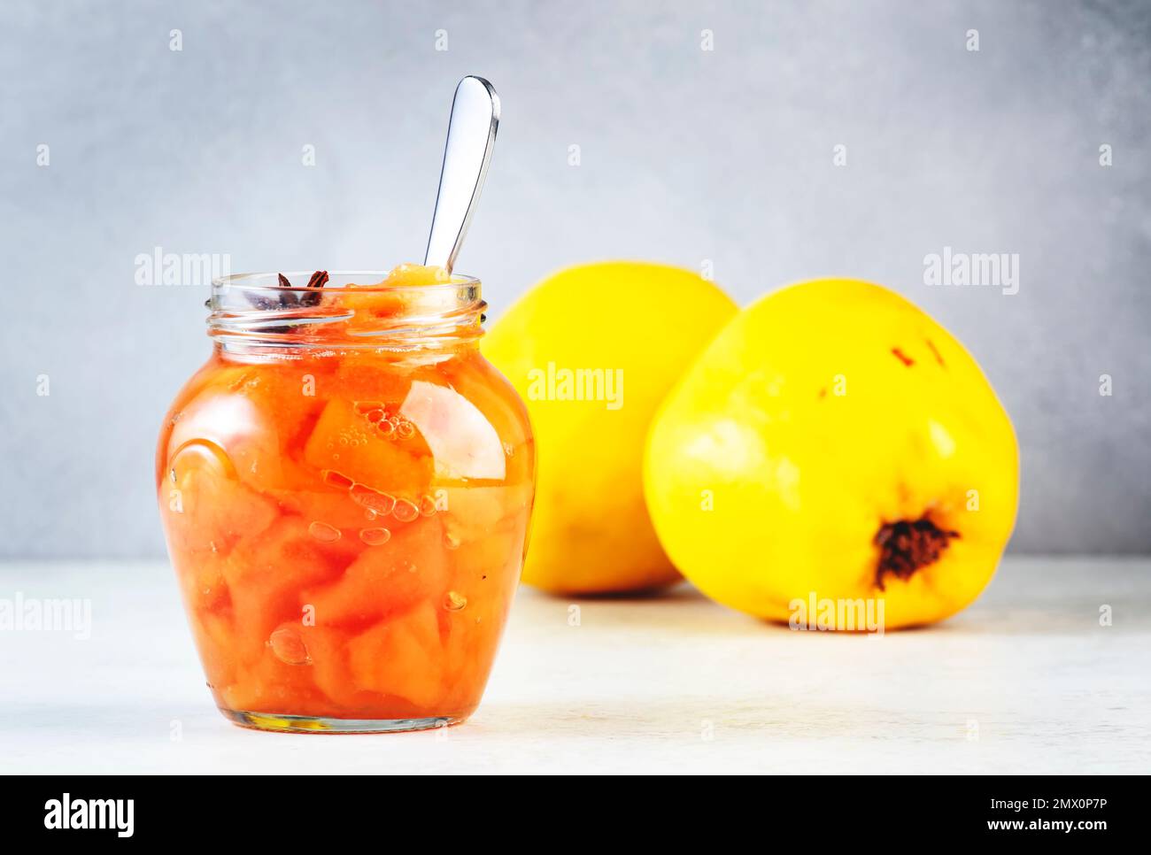 Confiture de coings ou confiture dans un pot en verre avec cannelle et anis sur fond de table de cuisine gris, espace de copie Banque D'Images