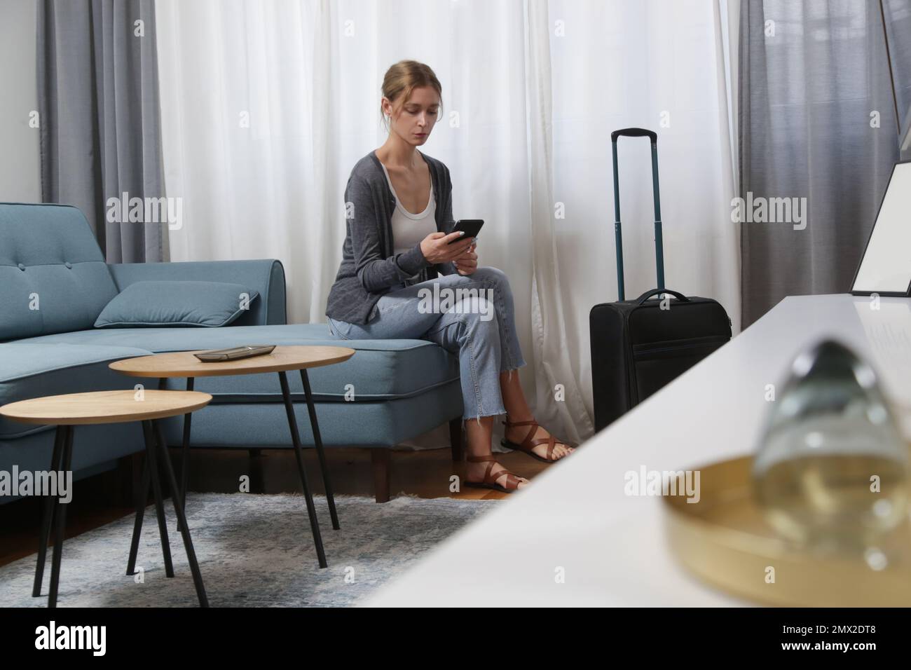 Jeune femme voyageant avec un smartphone et des bagages dans la chambre d'hôtel Banque D'Images