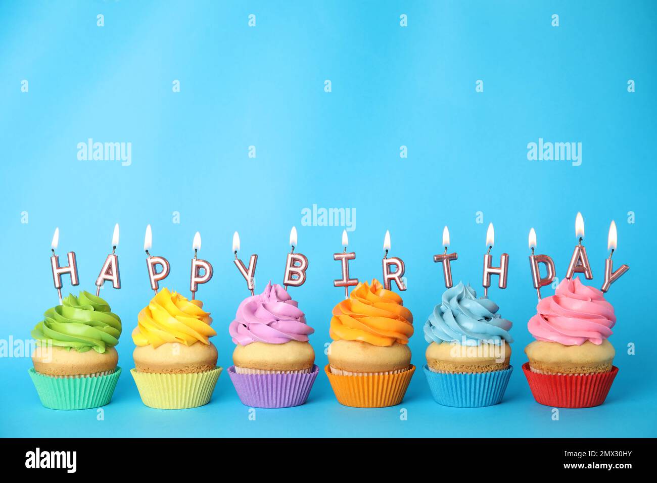 Cupcakes d'anniversaire avec bougies allumées sur fond bleu. Espace pour le texte Banque D'Images