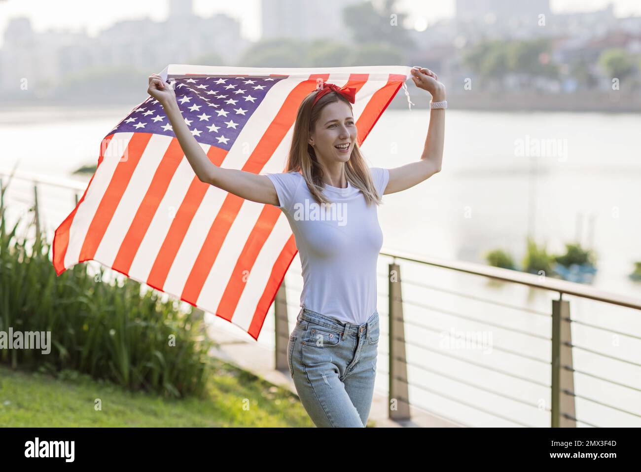 Vacances patriotiques. Bonne jeune femme caucasienne élégante avec drapeau  américain à l'extérieur au coucher du soleil. Les Etats-Unis célèbrent  l'indépendance le 4th juillet Photo Stock - Alamy