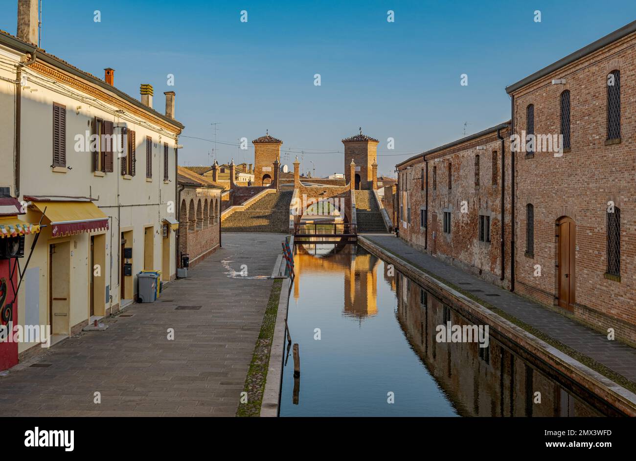 Vue en perspective d'un canal de Comacchio avec le célèbre pont à trois voies en arrière-plan. Comacchio, province de Ferrara, Emilie Romagne, Italie. Banque D'Images