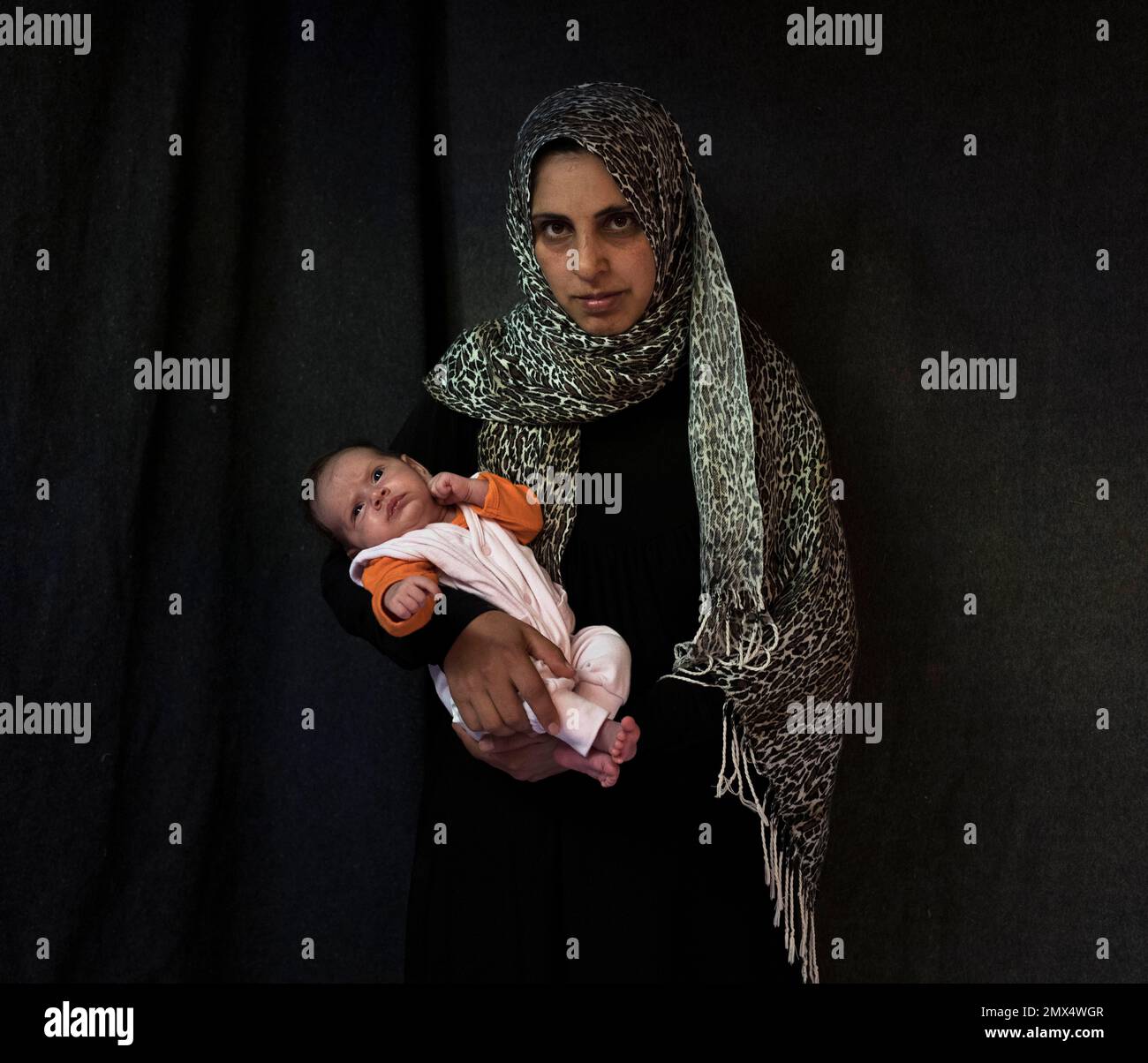 In this Tuesday Sept. 13, 2016 photo 35-year-old Siha Hamnad, a Syrian mother from Al Qunaytirah, poses with her baby girl Mona Alzaour in a tent made of blankets given by UNCHR at the Ritsona refugee camp in Greece. Siha is one of the hundreds of refugee women who gave birth while stranded in Greece. Mona, the family's fourth child, was born on Sunday, July 31, 2016 in the hospital of the nearby town of Chalkida. (AP Photo/Petros Giannakouris) Banque D'Images
