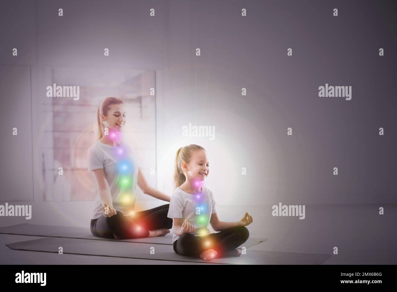 Mère et fille avec chakra points pratiquant le yoga en studio. Énergie de guérison Banque D'Images