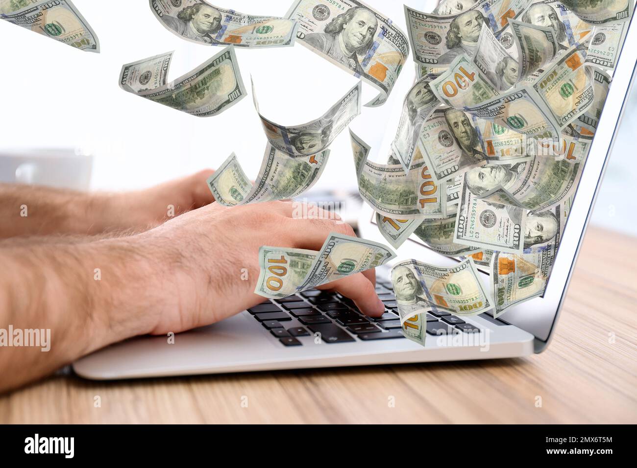 Homme avec un ordinateur portable moderne et des billets de banque en dollars à table, gros plan. Les gens font de l'argent en ligne Banque D'Images