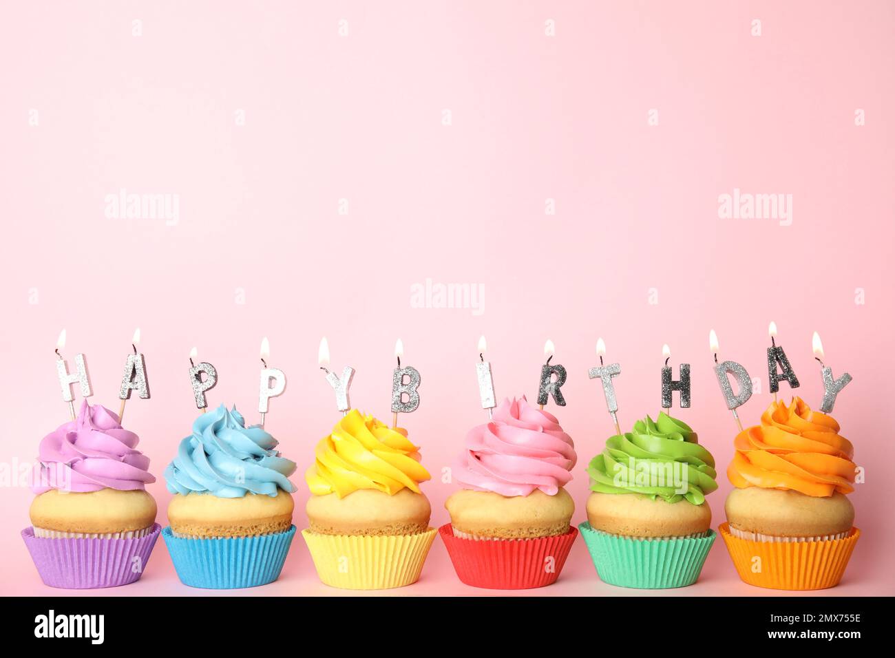 Cupcakes d'anniversaire avec bougies allumées sur fond rose. Espace pour le texte Banque D'Images