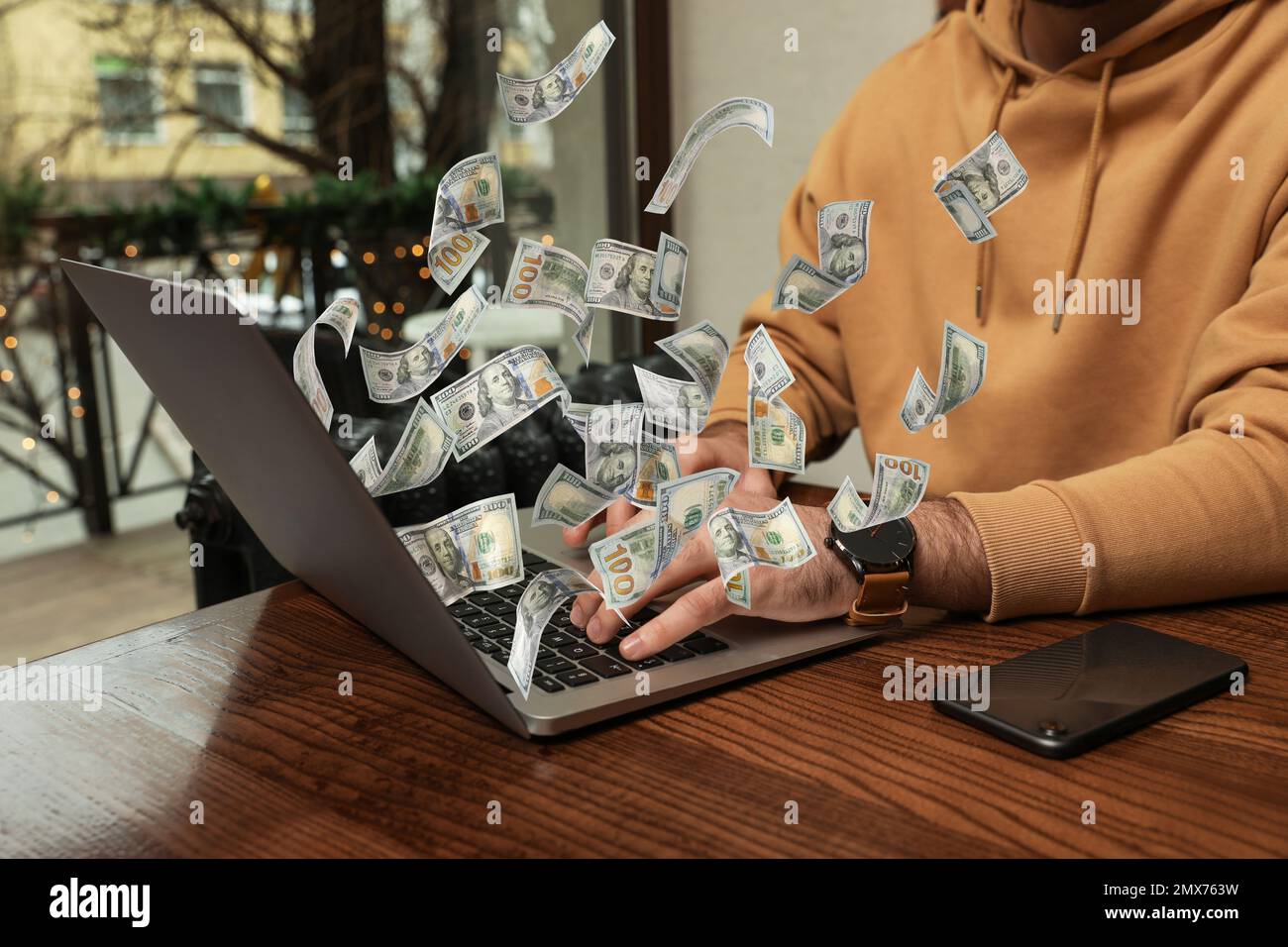 Homme avec un ordinateur portable moderne et des billets de banque en dollars à table à l'intérieur, gros plan. Les gens font de l'argent en ligne Banque D'Images