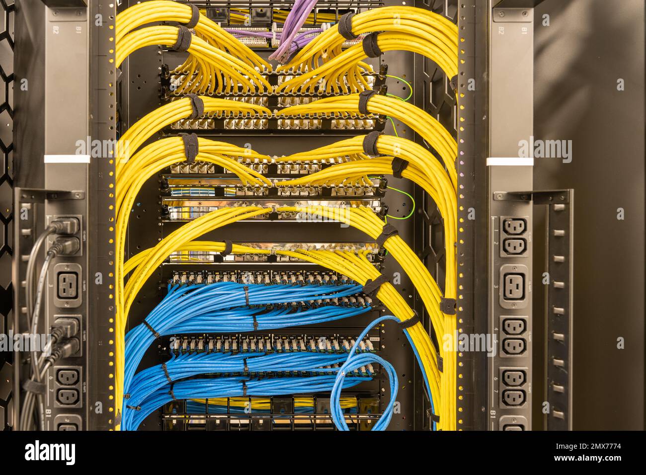 Rack avec prises d'alimentation sur le côté, plusieurs commutateurs et routeurs avec des câbles réseau correctement connectés, RJ45, centre de données, mise en réseau Banque D'Images