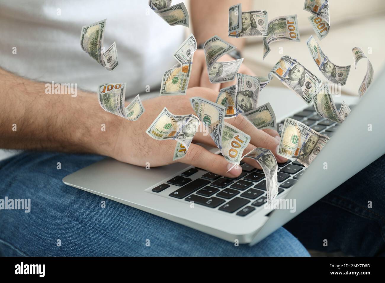 Homme avec un ordinateur portable moderne et des billets de banque en dollars à l'intérieur, gros plan. Les gens font de l'argent en ligne Banque D'Images